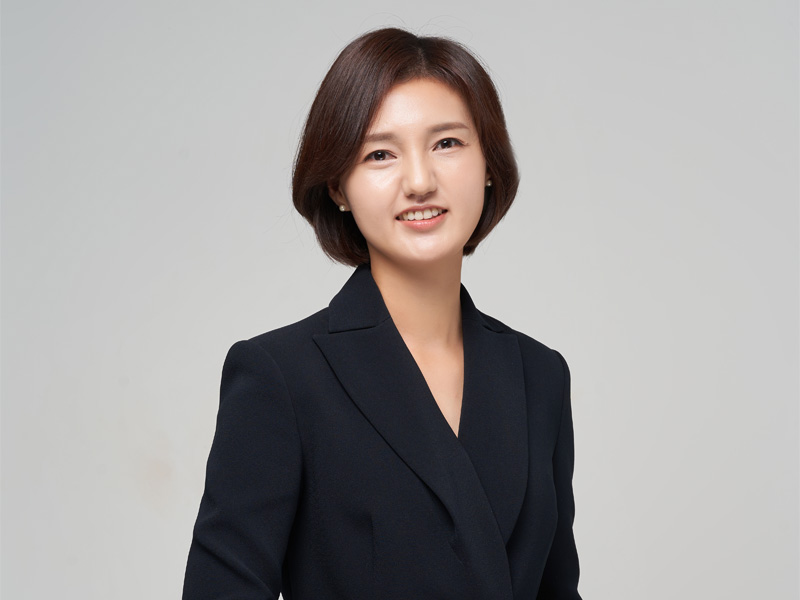 회색 배경의 정장 차림 여성 상반신 사진